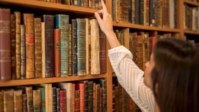 ahl female choosing book from bookshelf library