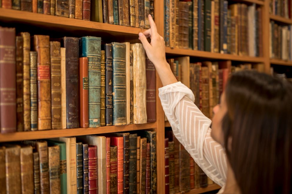 ahl female choosing book from bookshelf library