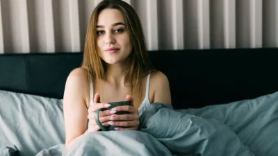 ahl portrait young woman drinking coffee bed home